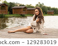 beautiful girl with long hair posing outdoors on the lake shore. 129283019