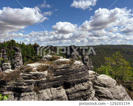 Aerial view of rugged black rock formations with dense green forest. Rock formations in the Saxon Switzerland Nature Park Aerial view of rugged black rock formations with dense green forest. Rock formations in the Saxon Switzerland Nature Park 129283154