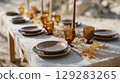 Cozy outdoor wedding dinner table with brown dinnerware and autumn leaves in mountain setting 129283265