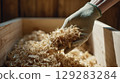 Hand wearing glove holding wood shavings in workshop environment 129283284