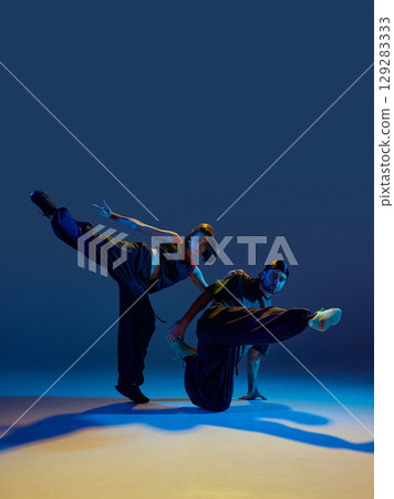 Hip hop pair balancing in wide stretch pose with intense focus and floor contact 129283333