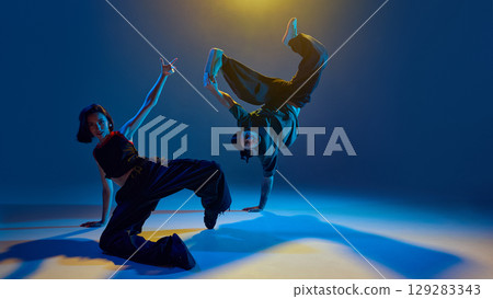 Dancers freezing in intense floor pose with raised limbs and direct eye contact 129283343