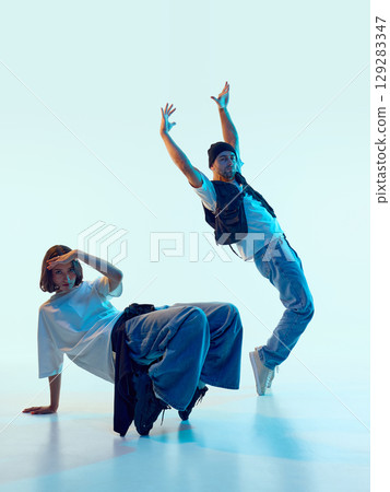 Male dancer arching backward with raised arms as female partner holds static pose 129283347