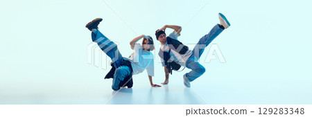 Expressive hip-hop dancers lifting legs in synchronized motion with serious facial focus. Banner 129283348