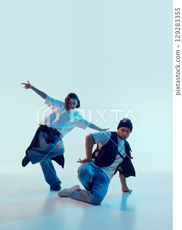 Hip-hop dancers posing in dynamic floor-level movement with dramatic focus 129283355
