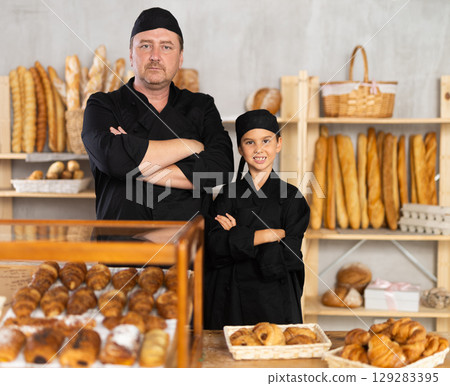 Father baker poses with his daughter in black chef uniform Father baker poses with his daughter in black chef uniform 129283395