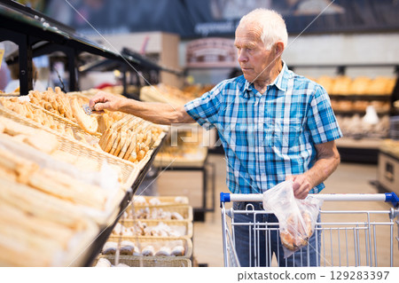 old age senor examines bakery products in the grocery section of the supermarket old age senor examines bakery products in the grocery section of the supermarket 129283397
