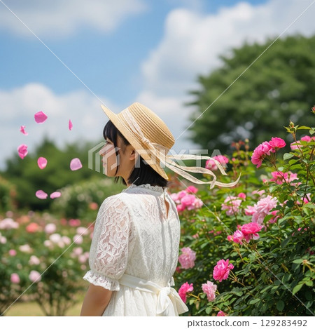 玫瑰田中一位戴著草帽的微笑女子的夏日肖像 玫瑰田中一位戴著草帽的微笑女子的夏日肖像 129283492