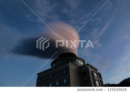 A hanging cloud like a UHO pierces a lightning rod 129283626