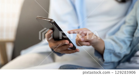 Digital Connection. Person interacting with smartphone in a cozy indoor setting. Digital Connection. Person interacting with smartphone in a cozy indoor setting. 129283906