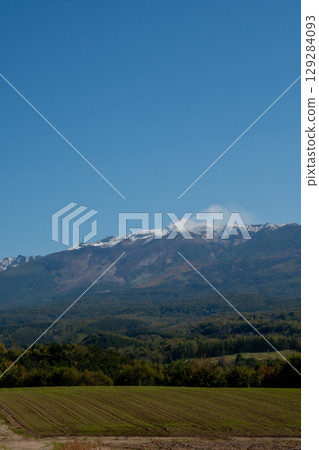 Autumnal farming areas and the snow-capped volcanic peak of Mt. Tokachi 129284093