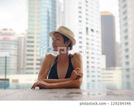 Young woman relaxing by the pool at a Kuala Lumpur hotel 129284346
