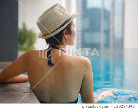 Young woman relaxing by the pool at a Kuala Lumpur hotel 129284348