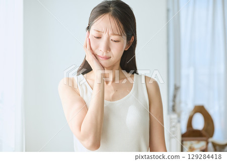 牙痛的女人,手摀臉,身穿白色背心的年輕女子 牙痛的女人,手摀臉,身穿白色背心的年輕女子 129284418