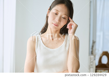 陷入沉思的女人,白色無袖,自然光,憂慮和焦慮 陷入沉思的女人,白色無袖,自然光,憂慮和焦慮 129284429