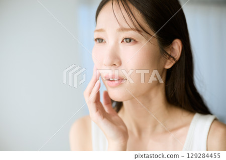 一位微笑、雙手放在皮膚上的女人 — — 非常適合美容和護膚的圖片 129284455