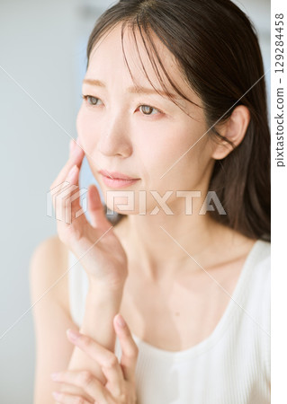 A smiling woman with her hands on her skin - ideal for beauty and skincare images 129284458