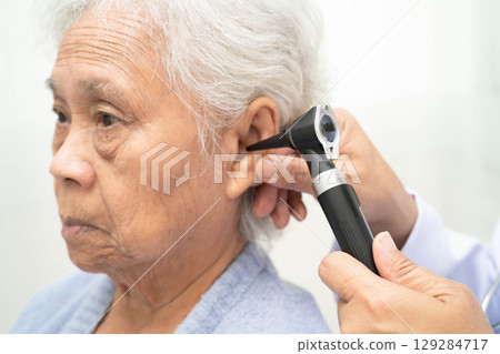 Otolaryngologist or ENT physician doctor examining senior patient ear with otoscope, hearing loss problem. Otolaryngologist or ENT physician doctor examining senior patient ear with otoscope, hearing loss problem. 129284717