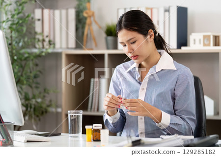 Office Syndrome: Woman managing medication for stress relief 129285182