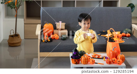 Creative Halloween Fun. A young boy enjoys crafting with festive decorations around him. 129285194