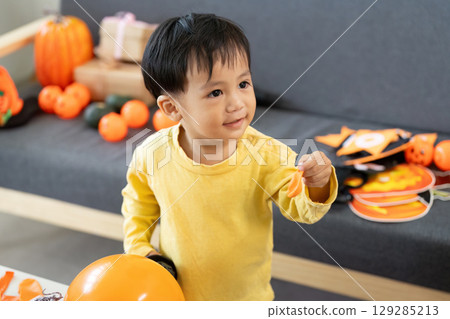 Halloween Joy. Toddler smiling while playing with festive decorations. Halloween Joy. Toddler smiling while playing with festive decorations. 129285213