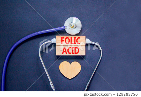 Folic acid symbol. Concept words Folic acid on beautiful wooden blocks. Wooden heart and stethoscope. Beautiful black background. Medical healthy lifestyle folic acid concept. Folic acid symbol. Concept words Folic acid on beautiful wooden blocks. Wooden heart and stethoscope. Beautiful black background. Medical healthy lifestyle folic acid concept. 129285750