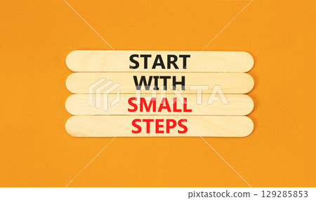 Start with small steps symbol. Concept words phrase Start with small steps on beautiful wooden stick. Beautiful orange paper background. Business Start with small steps concept. Copy space. Start with small steps symbol. Concept words phrase Start with small steps on beautiful wooden stick. Beautiful orange paper background. Business Start with small steps concept. Copy space. 129285853