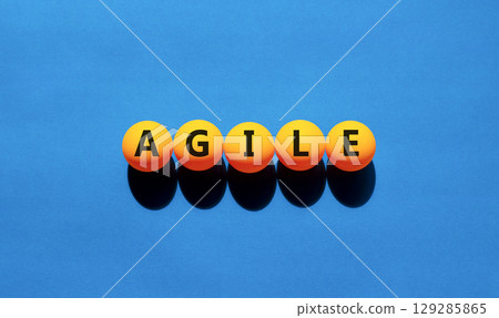 Agile symbol. Concept word Agile on beautiful yellow tennis ping pong balls. Beautiful wooden table wooden background. Business flexible and agile concept. Copy space. 129285865