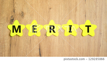 Merit symbol. Concept word Merit on beautiful yellow paper stars. Beautiful wooden table wooden background. Business lifestyle merit concept. Copy space. Merit symbol. Concept word Merit on beautiful yellow paper stars. Beautiful wooden table wooden background. Business lifestyle merit concept. Copy space. 129285866