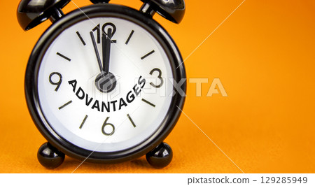 Advantages symbol. Concept word Advantages on beautiful orange paper. Beautiful orange paper background. Black alarm clock. Business advantages concept. Copy space. 129285949