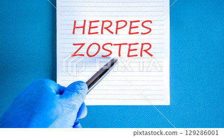 Herpes zoster symbol. Concept words Herpes zoster on beautiful white note. Doctor's hand in blue medical glove. Black pen. Beautiful blue background. Medical healthy lifestyle herpes zoster concept Herpes zoster symbol. Concept words Herpes zoster on beautiful white note. Doctor's hand in blue medical glove. Black pen. Beautiful blue background. Medical healthy lifestyle herpes zoster concept 129286001