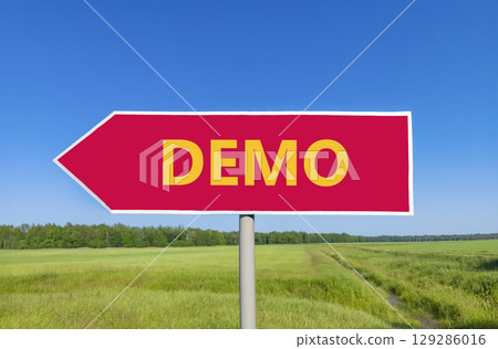 Demo symbol. Concept word Demo on beautiful red road sign. Beautiful blue sky green grass and forest peaceful nature background. Business and demo concept. Copy space. 129286016