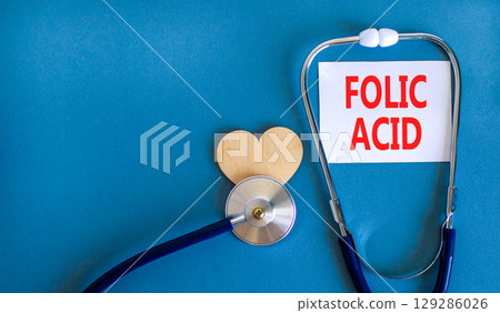 Folic acid symbol. Concept words Folic acid on beautiful white card. Wooden heart and stethoscope. Beautiful blue background. Medical healthy lifestyle folic acid concept. Folic acid symbol. Concept words Folic acid on beautiful white card. Wooden heart and stethoscope. Beautiful blue background. Medical healthy lifestyle folic acid concept. 129286026