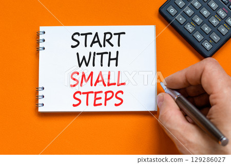 Start with small steps symbol. Concept words phrase Start with small steps on beautiful white note. Businessman's hand. Beautiful orange background. Business Start with small steps concept. Copy space 129286027