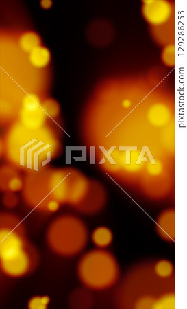 Glowing yellow particles float across a dark background in a vibrant bokeh-style abstract scene 129286253