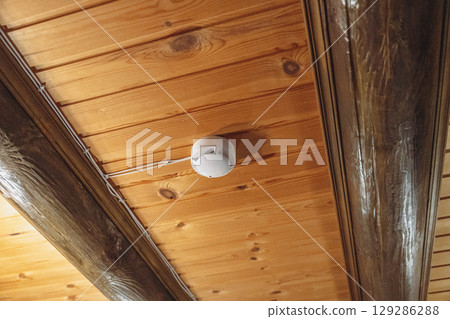 Smoke detector hanging on wooden ceiling ensuring safety 129286288