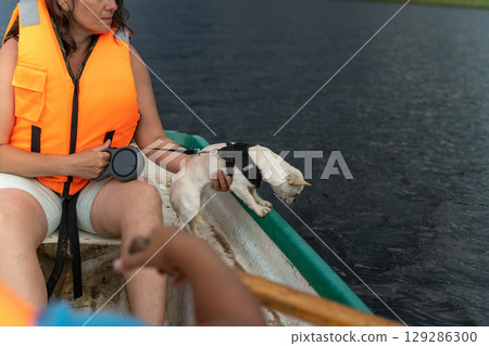 Small dog looking overboard a rowboat while wearing a harness Small dog looking overboard a rowboat while wearing a harness 129286300