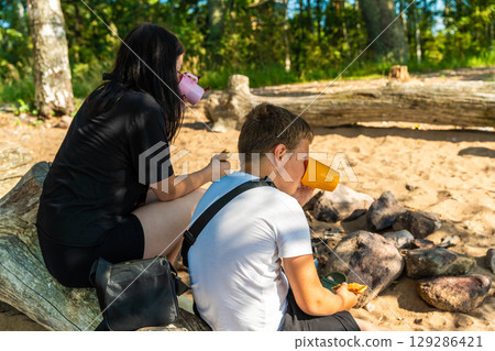 Teenagers enjoying a campfire snack and drink on the beach Teenagers enjoying a campfire snack and drink on the beach 129286421