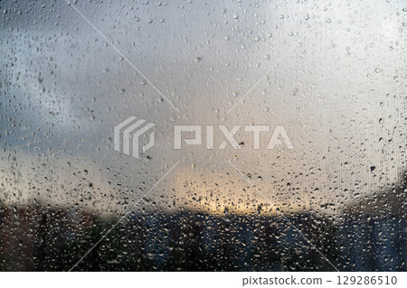 Raindrops on window with stormy sky at sunset 129286510