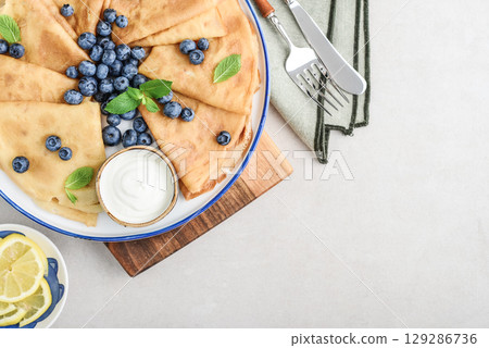 Homemade thin pancakes (crepes) with fresh blueberries and sour cream Homemade thin pancakes (crepes) with fresh blueberries and sour cream 129286736