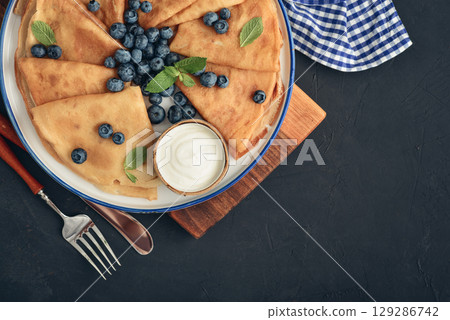 Homemade thin pancakes (crepes) with fresh blueberries and sour cream 129286742