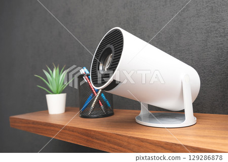 White projector with a lens on shelf 129286878