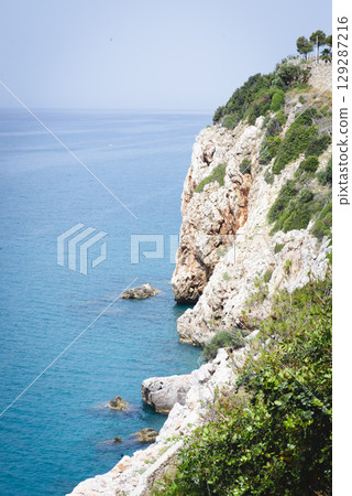 Stunning view of Calella de Palafrugell's pristine coastline featuring traditional whitewashed Mediterranean architecture, crystal-clear turquoise waters, and dramatic rocky outcrops along Costa Brava 129287216