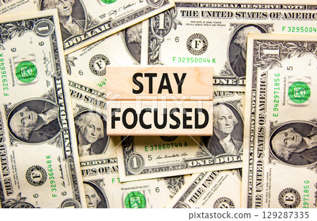 Stay focused symbol. Concept words Stay focused on wooden blocks on a beautiful background from dollar bills. Business, support, motivation, psychological and stay focused concept. Copy space. 129287335