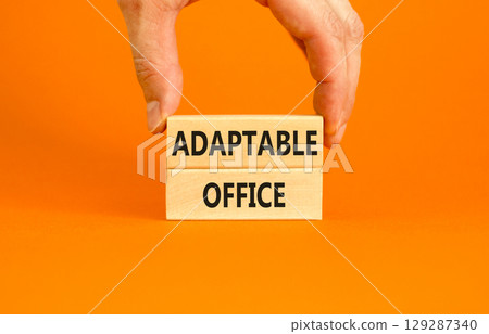 Adaptable office symbol. Concept words Adaptable office on beautiful wooden block. Beautiful orange paper background. Businessman hand. Business Adaptable office concept. Copy space. Adaptable office symbol. Concept words Adaptable office on beautiful wooden block. Beautiful orange paper background. Businessman hand. Business Adaptable office concept. Copy space. 129287340