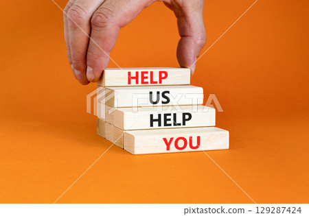 Help you symbol. Concept words phrase Help us help you on beautiful wooden blocks. Beautiful orange paper background. Businessman's hand. Business Help you concept. Copy space. 129287424