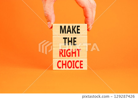 Make the right choice symbol. Concept words phrase Make the right choice on beautiful wooden blocks. Beautiful orange background. Businessman's hand. Business Make the right choice concept. Copy space 129287426