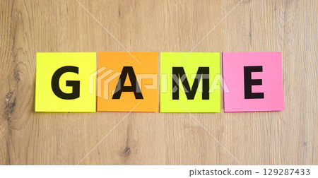 Game symbol. Concept word Game on beautiful colored paper. Beautiful wooden table wooden background. Business, lifestyle and game concept. Copy space. Game symbol. Concept word Game on beautiful colored paper. Beautiful wooden table wooden background. Business, lifestyle and game concept. Copy space. 129287433