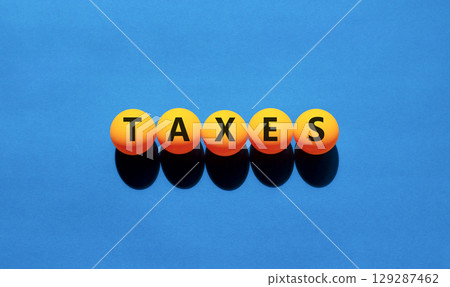 Taxes symbol. Concept word Taxes on beautiful yellow tennis ping pong balls. Beautiful wooden table wooden background. Business lifestyle taxes concept. Copy space. 129287462