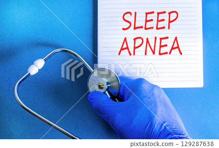 Sleep apnea symbol. Concept words Sleep apnea on beautiful white note. Doctor's hand in blue medical glove. Stethoscope. Beautiful blue background. Medical healthy lifestyle sleep apnea concept. 129287638
